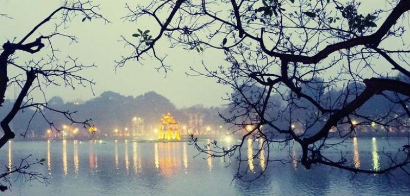 Một khung cảnh ăn đêm Hà Nội mang nét hoài niệm, với ánh sáng đèn vàng ấm áp và những người ngồi quây quần bên bàn ăn đơn giản.